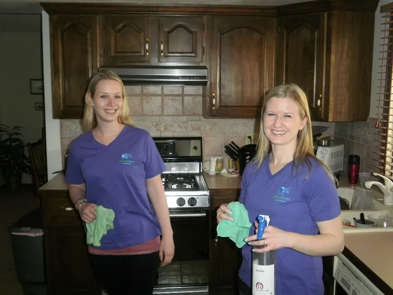 Two GreenClean Colorado cleaners smiling in a kitchen with cleaning cloths